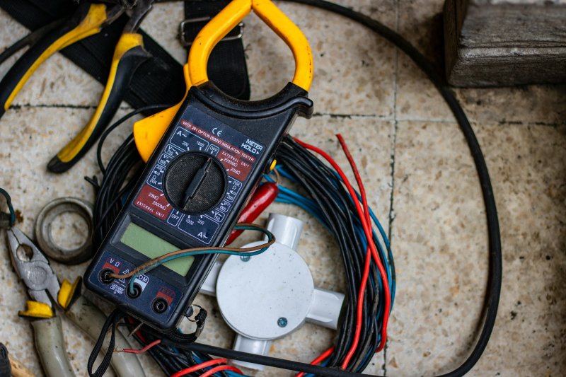 Digital multimeter and electrical hand tools laid out for a service call