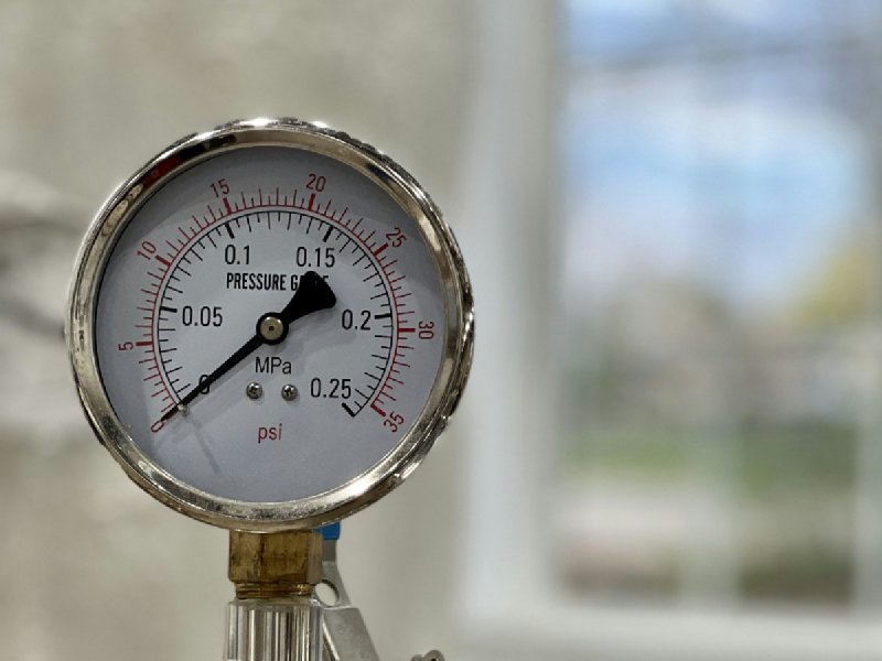 Pressure gauge on a metal pipe showing scales in MPa and psi