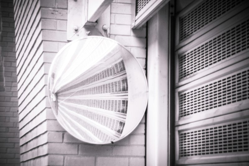 Circular metal exterior wall vent with slatted grille on a brick wall