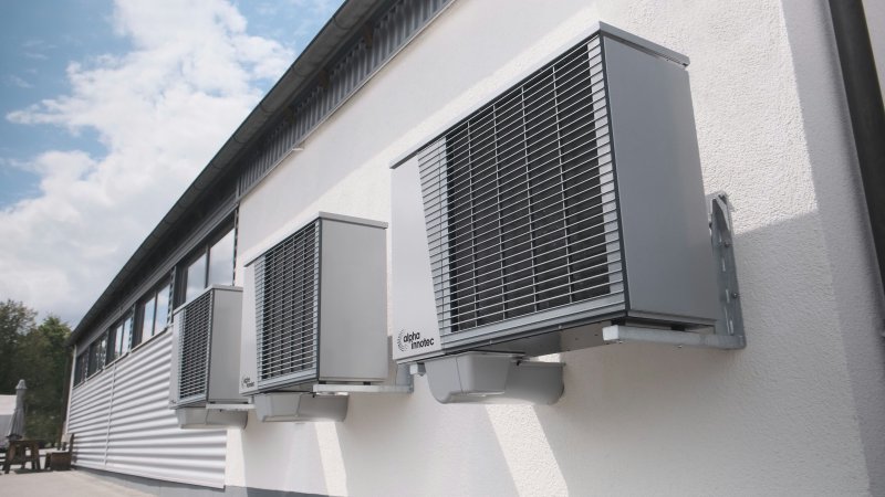 Three outdoor mini-split condenser units mounted side by side on an exterior wall