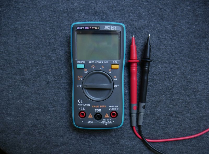 Digital multimeter with red and black test probes for resistance and voltage diagnostics