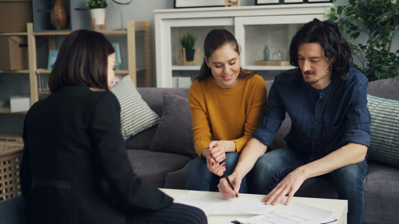 Couple signing service paperwork with a professional at a table