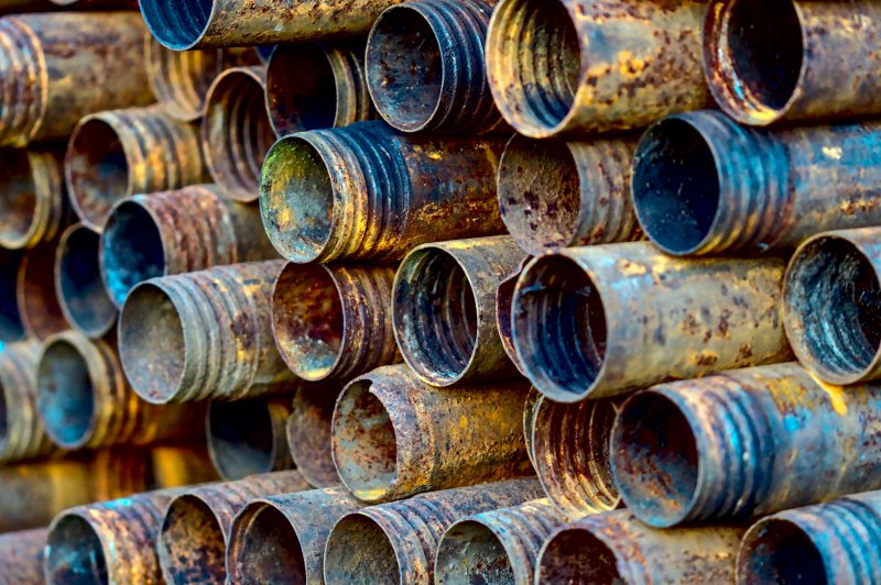Stack of rusted threaded steel pipes showing internal corrosion
