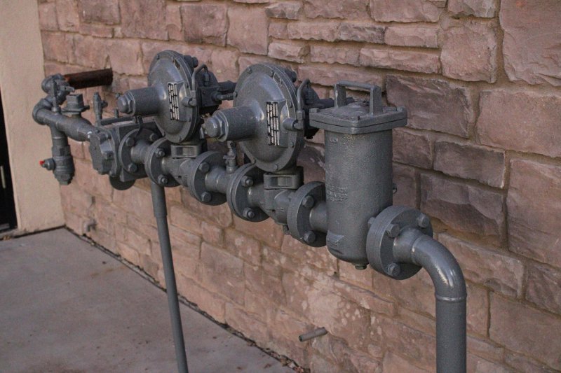 Industrial gas valve assembly with pressure gauges, shutoff handle, and filter on a utility wall