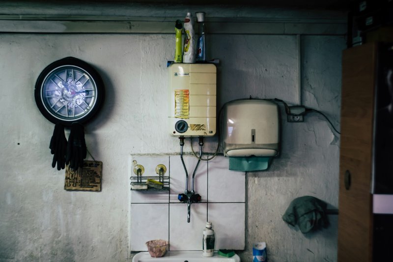 Wall-mounted tankless-style water heater connected to supply piping in a utility room