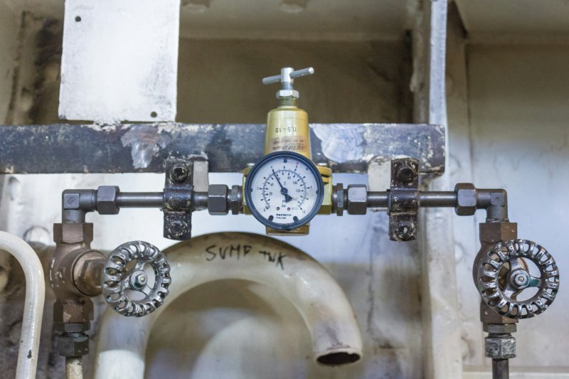 Industrial pressure gauge mounted on a pipe system with valves above a tank
