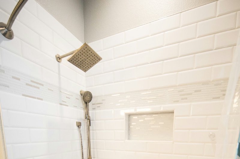White tiled walk-in shower with chrome fixtures after a tub-to-shower conversion