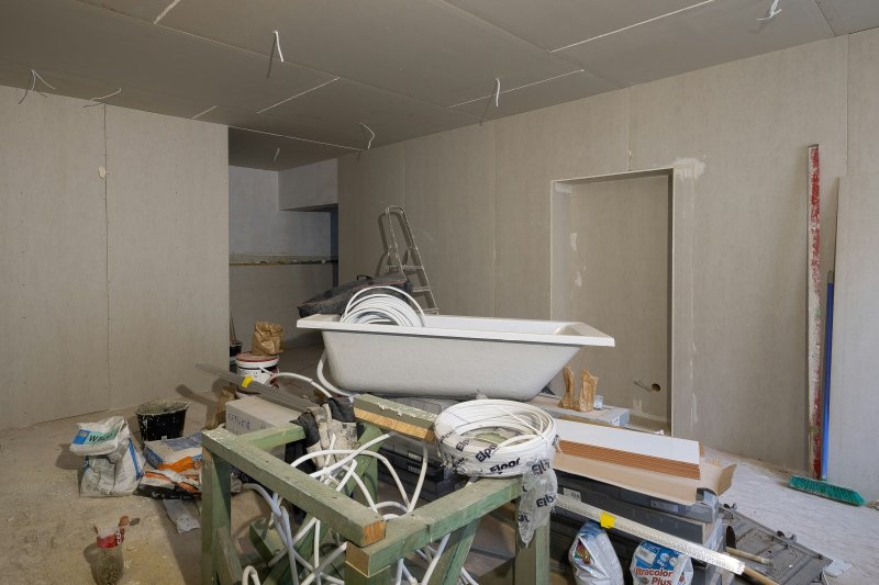 Bathroom mid-demo with exposed drywall, plumbing pipes, and a bathtub still in place