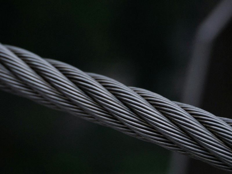 Close-up of a twisted galvanized steel cable showing its braided wire-rope construction