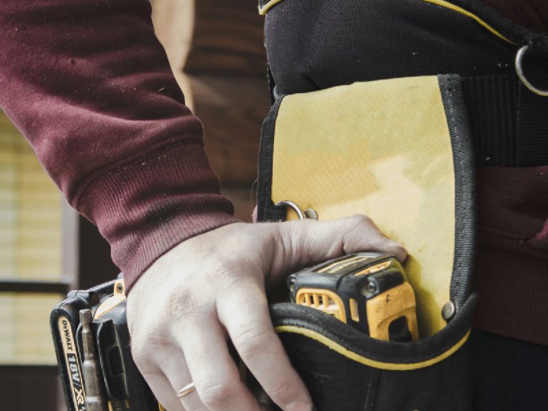 A technician in a tool belt holding a cordless drill