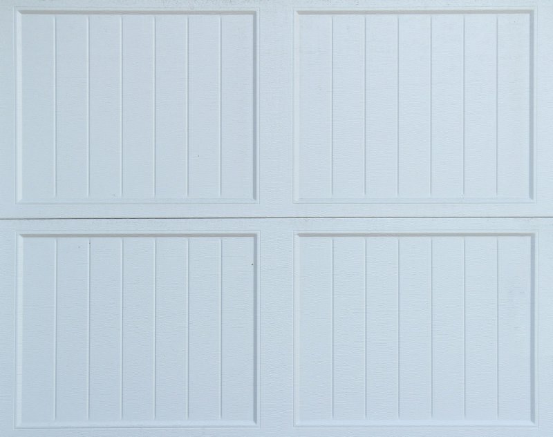 White sectional garage door with four rectangular raised panels and vertical grooves
