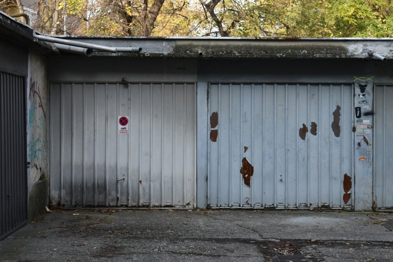Weathered metal garage doors with rust spots, peeling paint, and graffiti