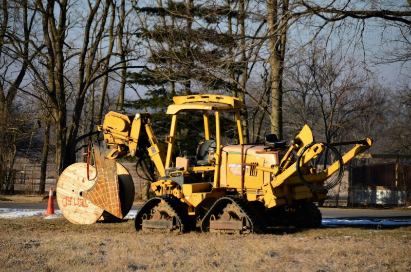 Yellow walk-behind utility trencher parked on grass, the type rented for $200 per day on DIY drain projects