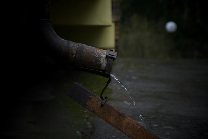 Rusted metal pipe leaking water onto a dark ground surface — the burst-pipe scenario behind most HO-3 emergency-extraction claims