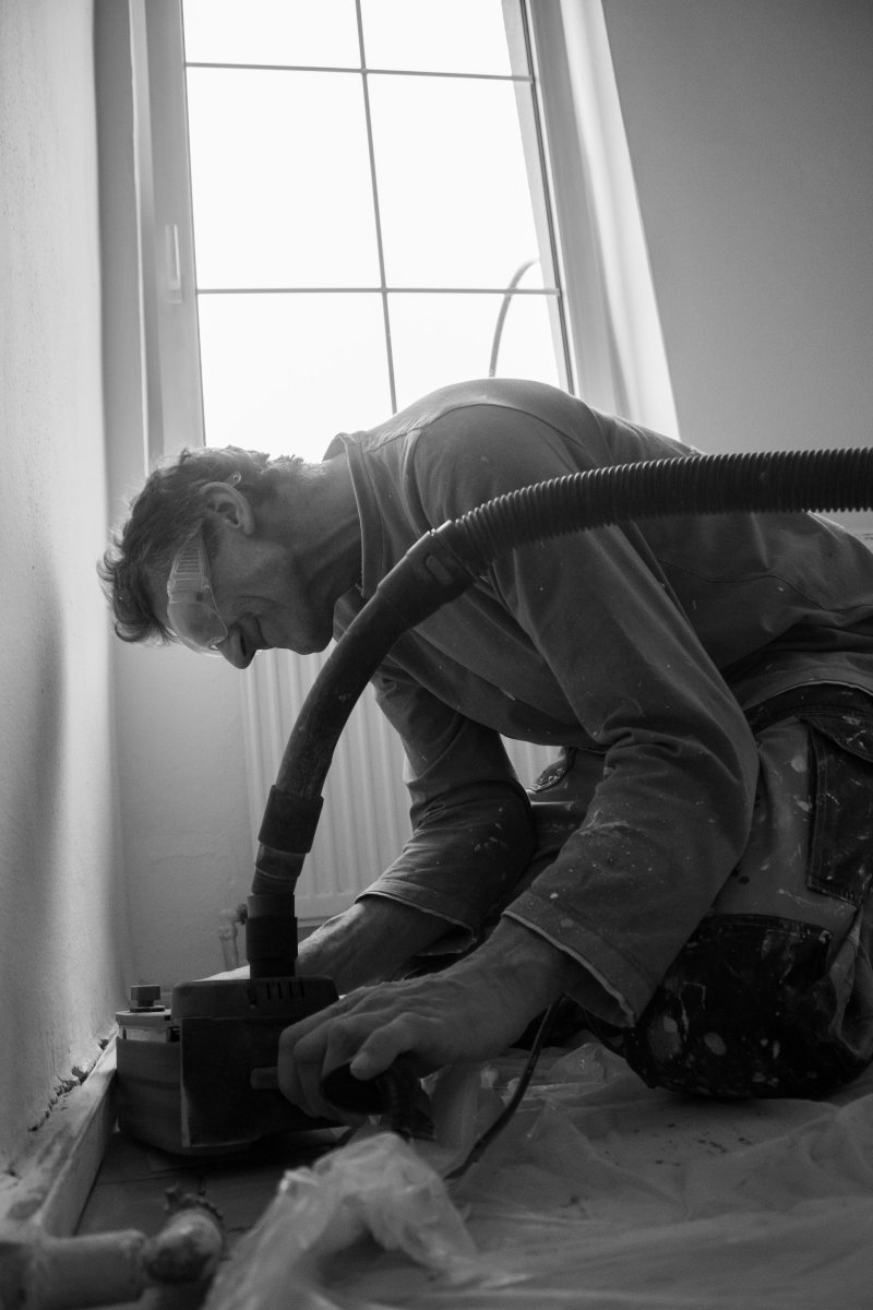 Restoration technician in protective gear handling a vacuum extraction hose
