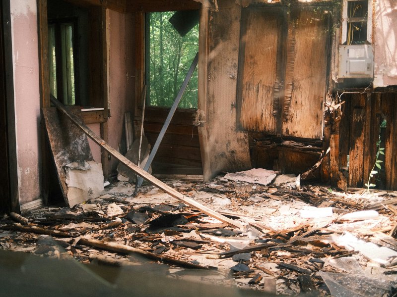 Fire-damaged residential interior with charred walls, soot, and debris