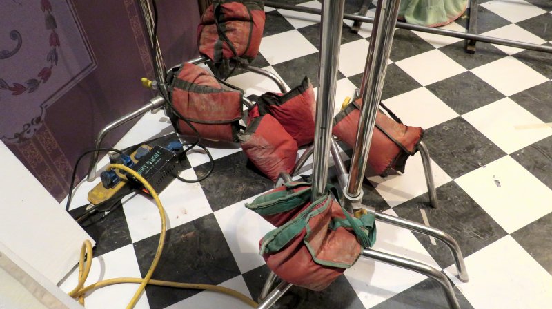 Rows of red flood-barrier sandbags fixed to metal stands, staged with cabling and a power unit on a checkered floor