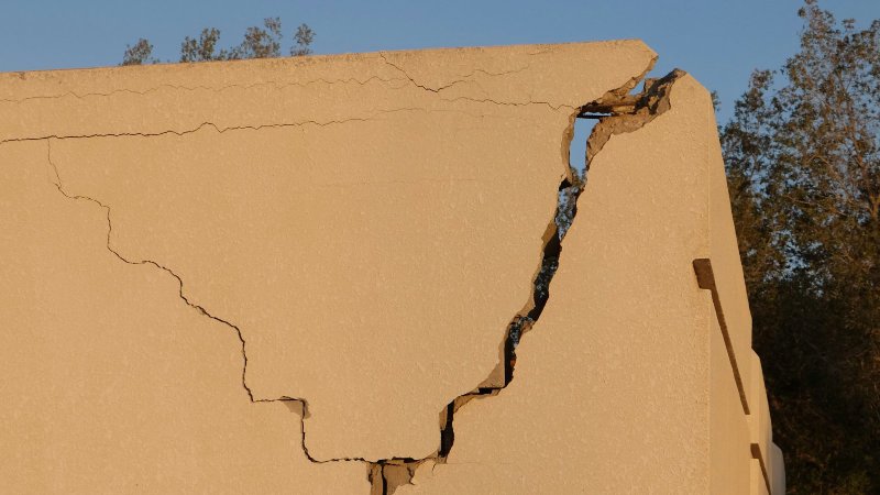 Large vertical crack running top to bottom through a light-colored concrete foundation wall