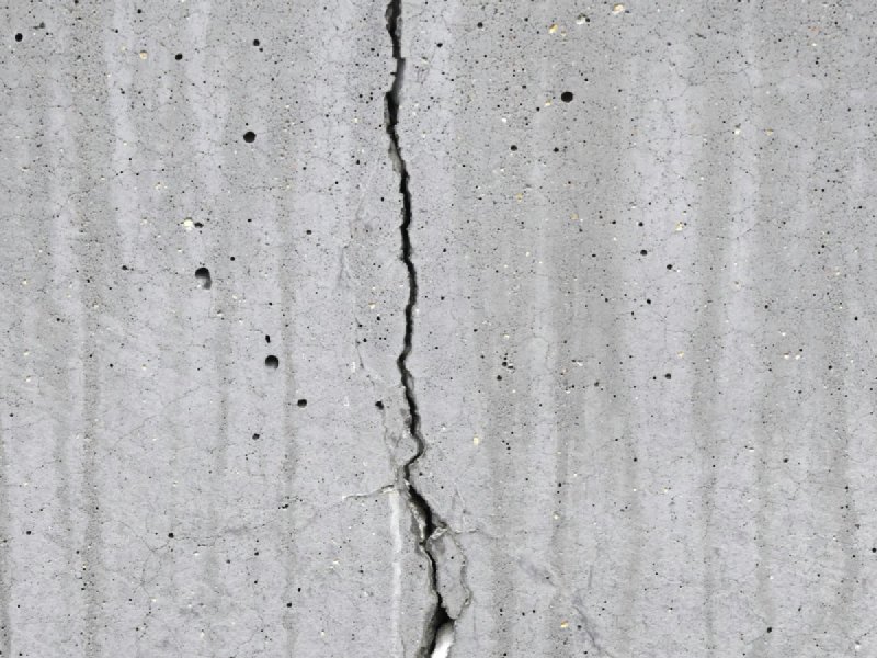 Vertical crack running through a gray concrete foundation wall