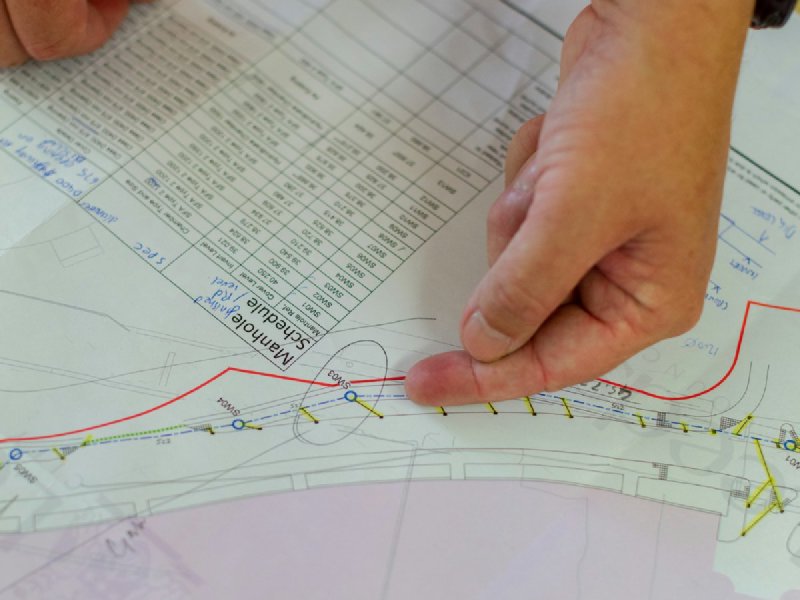Hands pointing at a detailed construction blueprint on a wooden table