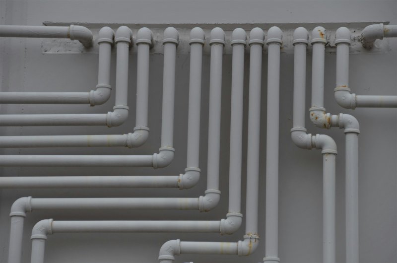 White PVC pipe network mounted on a wall, typical of radon mitigation routing