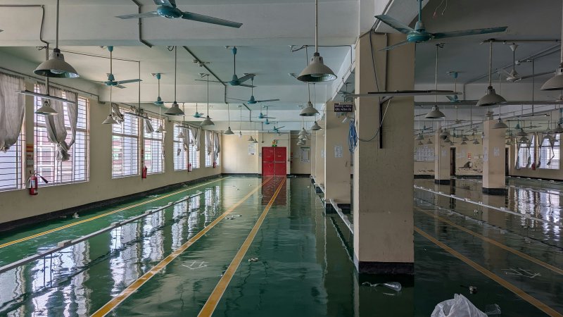 Flooded large interior space with rows of overhead fans running, illustrating commercial-scale water mitigation drying operation