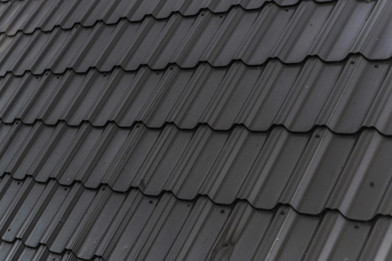 Close-up of dark gray corrugated metal roof panels with exposed fasteners