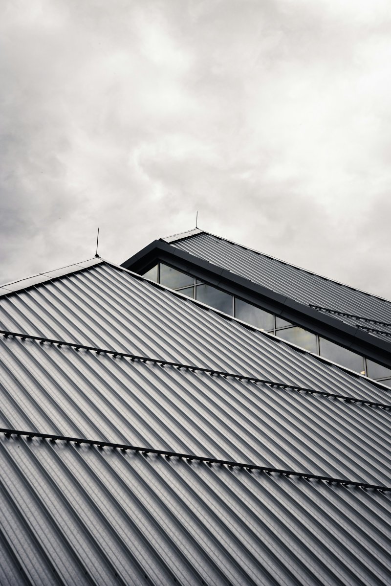 Modern building clad in corrugated metal roofing under a cloudy sky