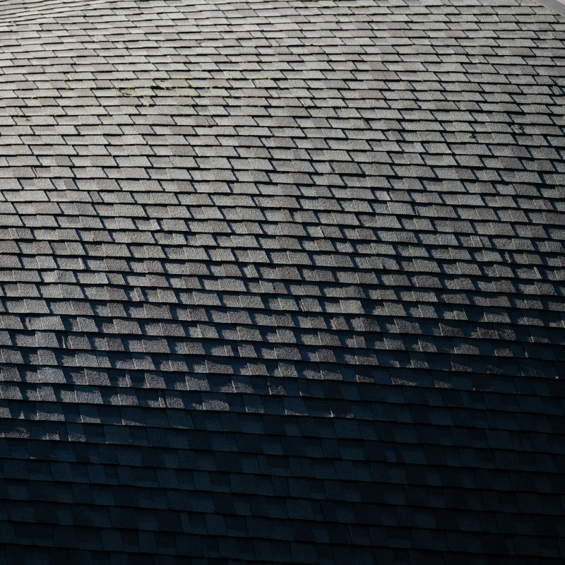 Gray architectural asphalt shingles on a sloped residential roof, showing the laminated dimensional pattern that covers most U.S. reroofs