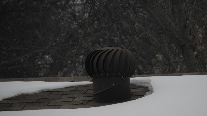 Black plastic roof vent installed near the ridge of a residential shingle roof