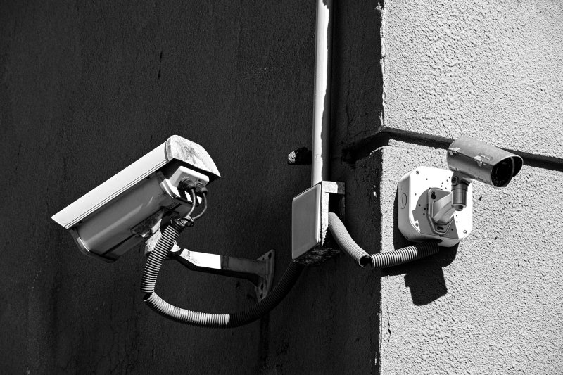Two exterior security cameras mounted at a building corner, covering both elevations