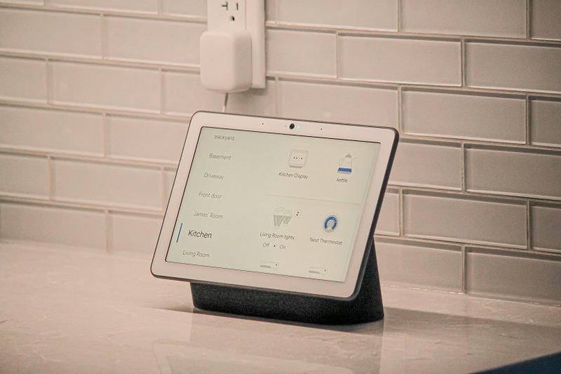 Smart home display on a kitchen counter showing room and device controls including kitchen, living room lights, and Nest thermostat